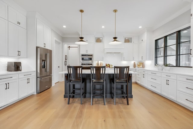 kitchen featuring appliances with stainless steel finishes, hanging light fixtures, white cabinets, a kitchen island, and decorative backsplash