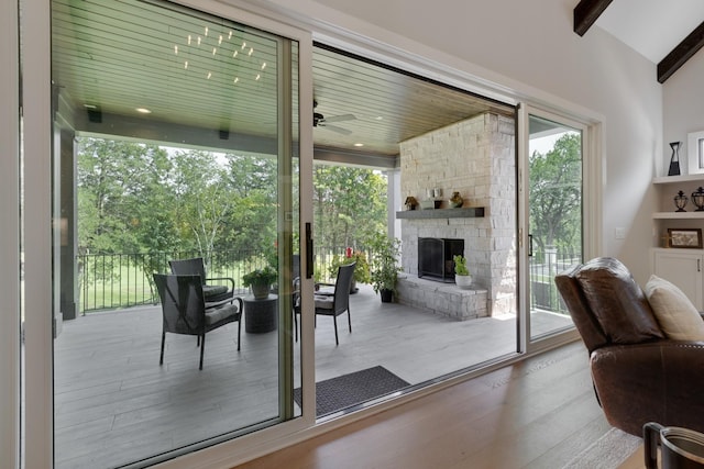 entryway with light hardwood / wood-style flooring, vaulted ceiling with beams, a fireplace, and ceiling fan