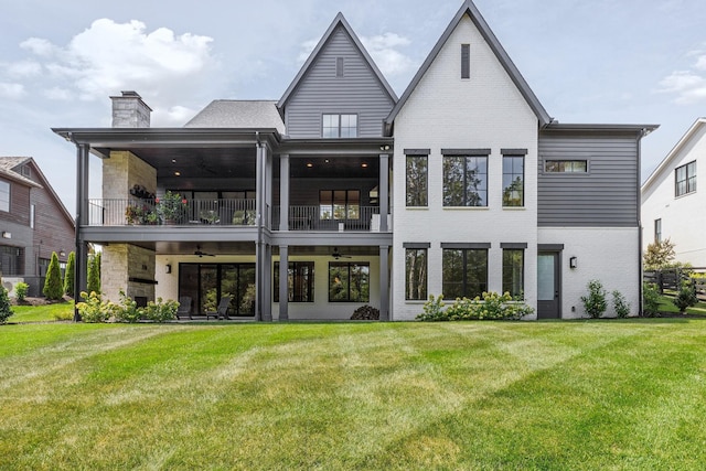 rear view of house with ceiling fan, a lawn, and a balcony