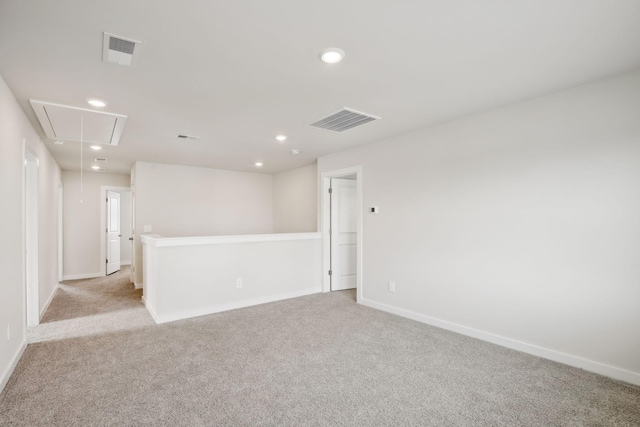 unfurnished room featuring attic access, light colored carpet, visible vents, and baseboards