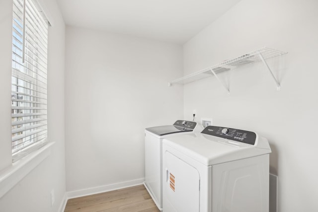 washroom featuring laundry area, baseboards, light wood finished floors, and separate washer and dryer