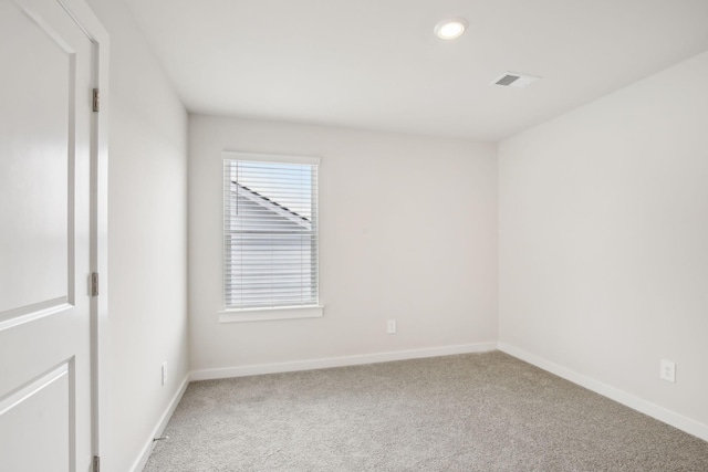 carpeted spare room featuring visible vents and baseboards