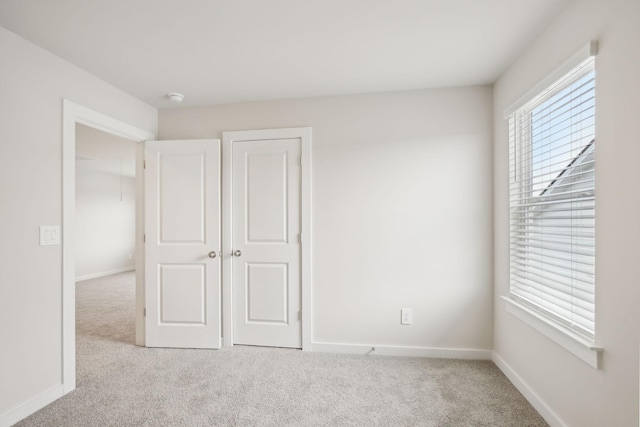 unfurnished bedroom with light colored carpet, multiple windows, and baseboards