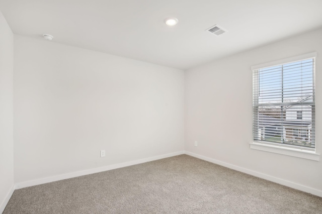 carpeted empty room with visible vents and baseboards