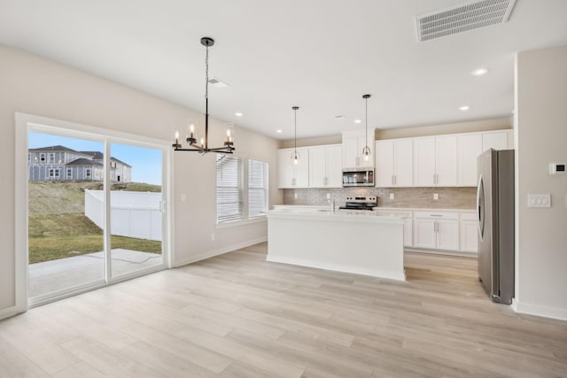 kitchen with visible vents, white cabinetry, hanging light fixtures, appliances with stainless steel finishes, and light countertops