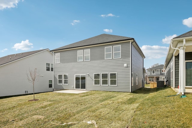 back of property with roof with shingles, a lawn, and a patio