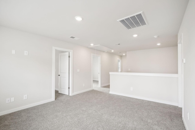 unfurnished room with light carpet, attic access, visible vents, baseboards, and recessed lighting