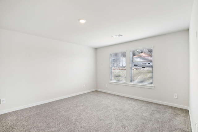 carpeted spare room with visible vents and baseboards