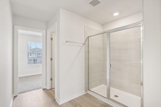 bathroom featuring visible vents, a shower stall, baseboards, and wood finished floors