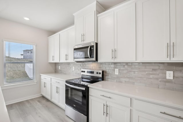 kitchen featuring tasteful backsplash, light wood-style flooring, appliances with stainless steel finishes, light countertops, and white cabinetry