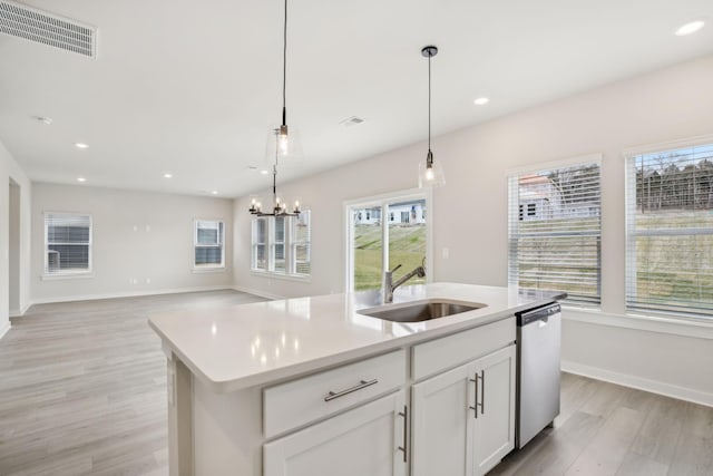 kitchen featuring decorative light fixtures, visible vents, a kitchen island with sink, a sink, and dishwasher