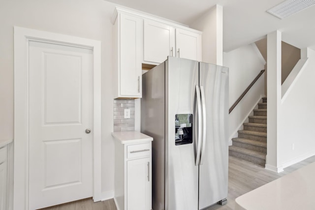 kitchen featuring visible vents, white cabinetry, stainless steel refrigerator with ice dispenser, and light countertops