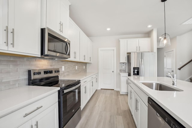 kitchen featuring stainless steel appliances, white cabinets, light countertops, and hanging light fixtures