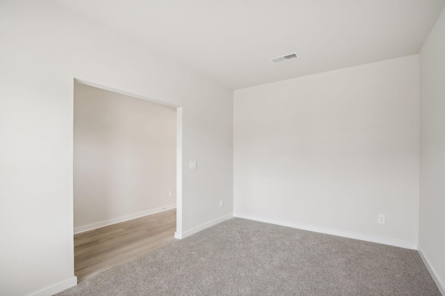 empty room with light carpet, visible vents, and baseboards