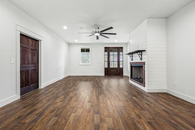 unfurnished living room with a fireplace, dark wood-type flooring, and ceiling fan