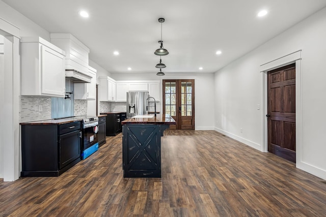 kitchen with white cabinetry, a center island with sink, appliances with stainless steel finishes, dark hardwood / wood-style flooring, and pendant lighting