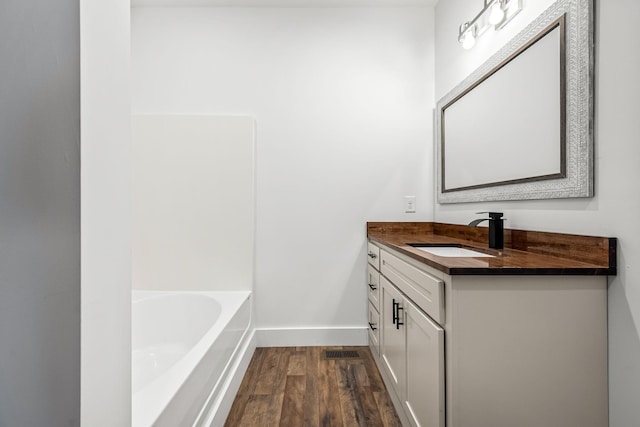 bathroom featuring vanity, a tub to relax in, and wood-type flooring