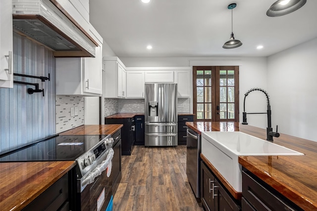 kitchen with white cabinetry, custom exhaust hood, stainless steel appliances, and wooden counters