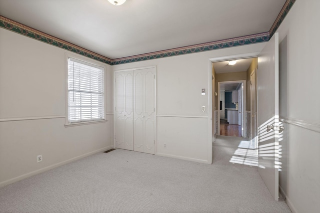 unfurnished bedroom featuring light carpet and a closet