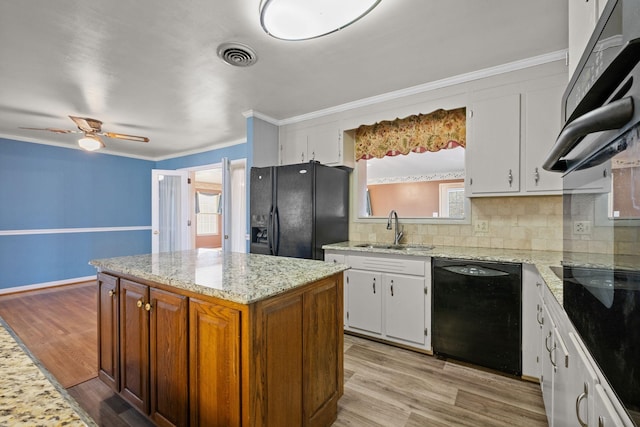 kitchen featuring sink, white cabinetry, a center island, light hardwood / wood-style floors, and black appliances