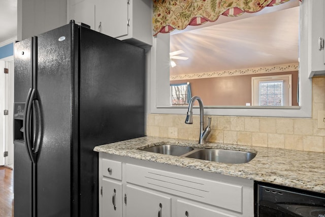 kitchen with white cabinetry, sink, decorative backsplash, black appliances, and light stone countertops