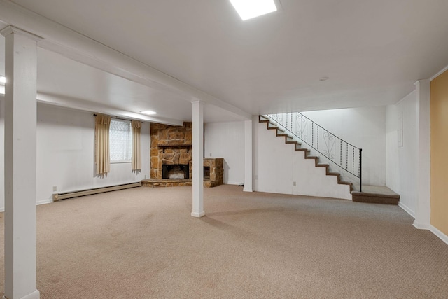 unfurnished living room featuring a baseboard radiator, a stone fireplace, and carpet