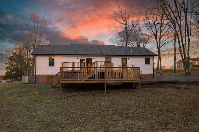 back house at dusk featuring a yard and a deck