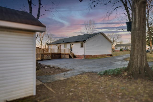 property exterior at dusk featuring a wooden deck