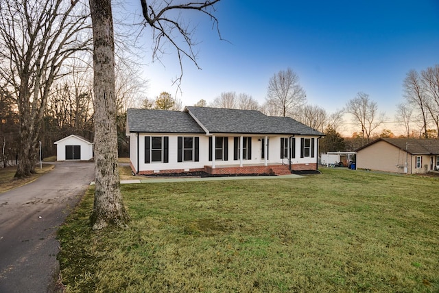 ranch-style house featuring a garage, a porch, an outdoor structure, and a yard