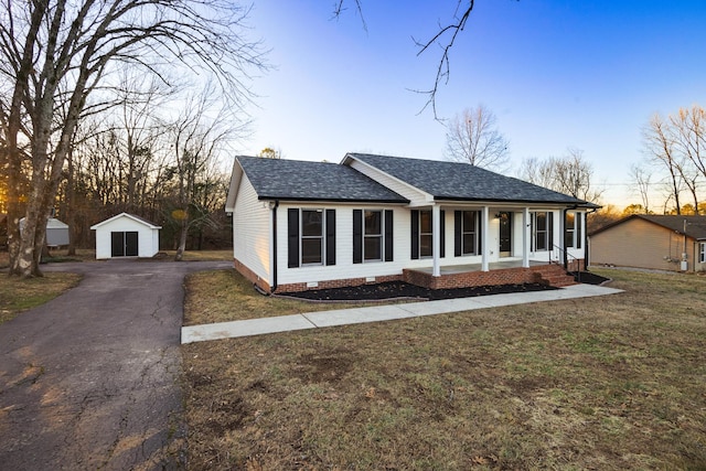 single story home featuring a storage shed, a lawn, and covered porch