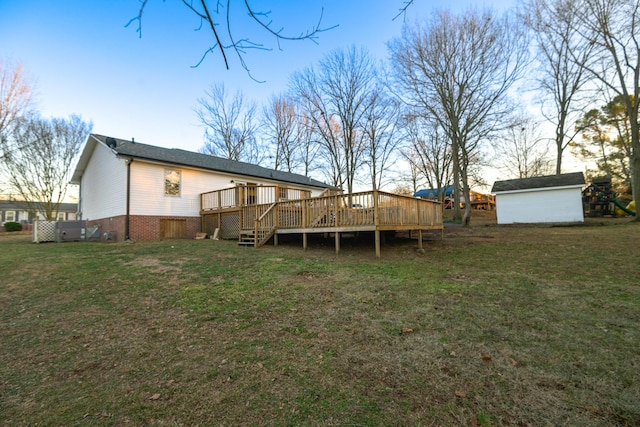 rear view of property featuring a yard, a deck, and a storage shed