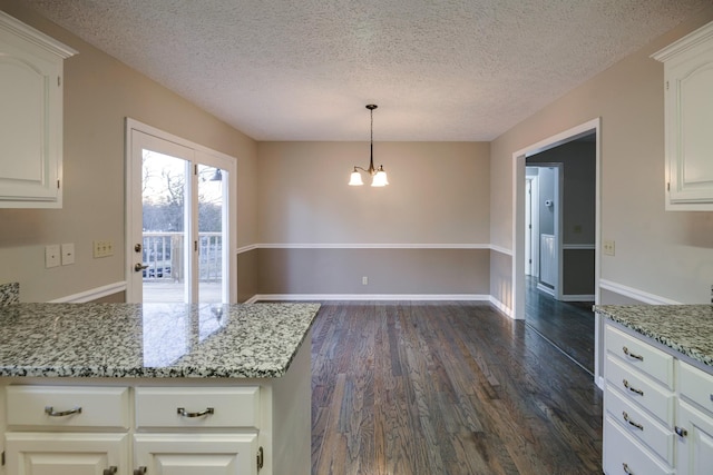 kitchen with light stone counters, a textured ceiling, and white cabinets