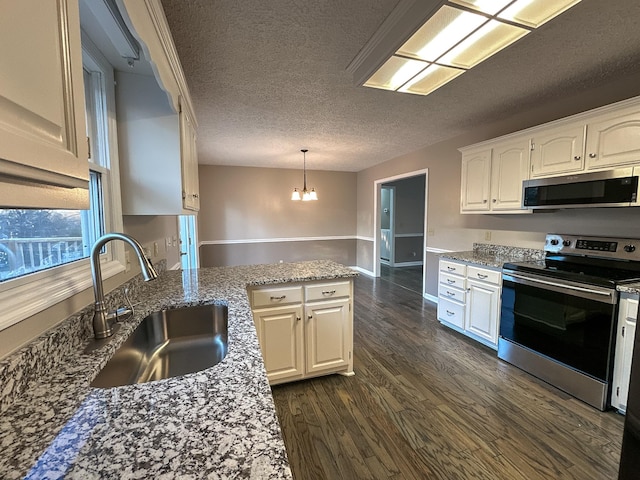 kitchen with decorative light fixtures, white cabinetry, sink, stainless steel appliances, and a textured ceiling