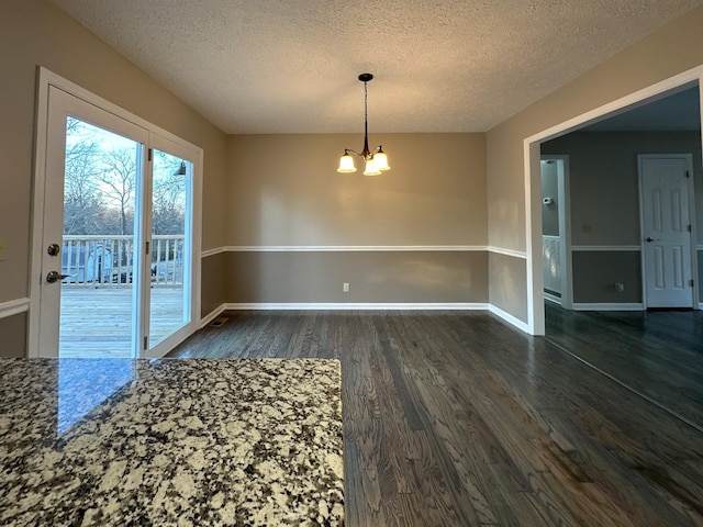 unfurnished dining area featuring an inviting chandelier, dark hardwood / wood-style floors, and a textured ceiling