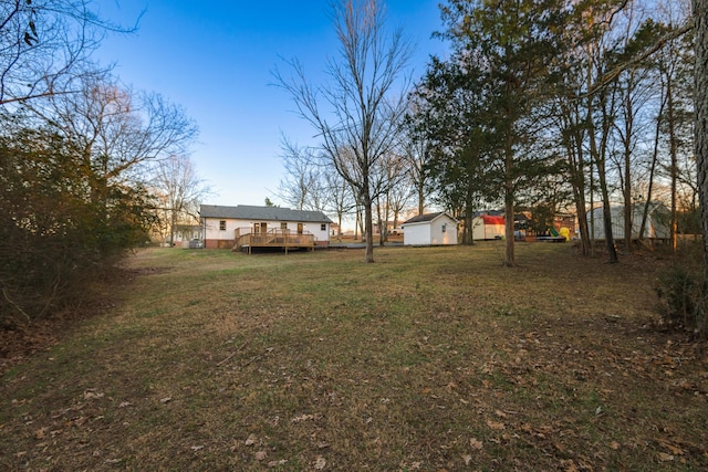 view of yard featuring a wooden deck and a storage shed