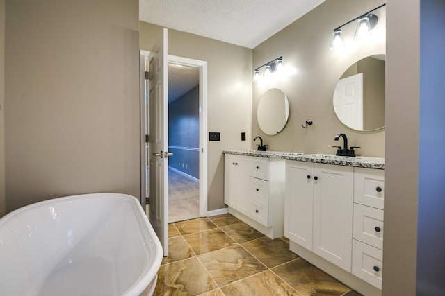 bathroom with vanity, a textured ceiling, and a washtub