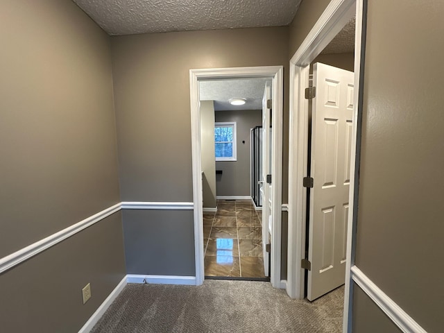 hallway with carpet flooring and a textured ceiling