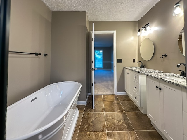 bathroom featuring vanity, a tub to relax in, and a textured ceiling