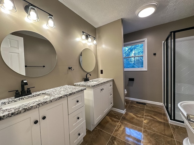 bathroom with vanity, toilet, a shower with shower door, and a textured ceiling