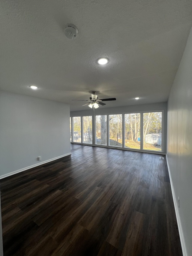 empty room featuring a healthy amount of sunlight, dark wood-type flooring, and a textured ceiling