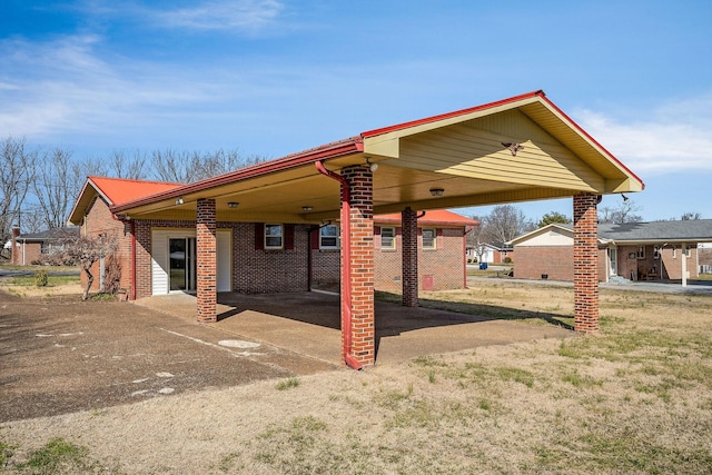 exterior space featuring metal roof, a carport, brick siding, and driveway