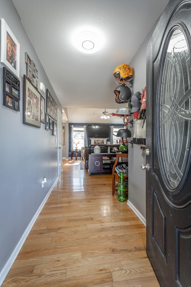 interior space with ceiling fan, a textured ceiling, and light wood-type flooring