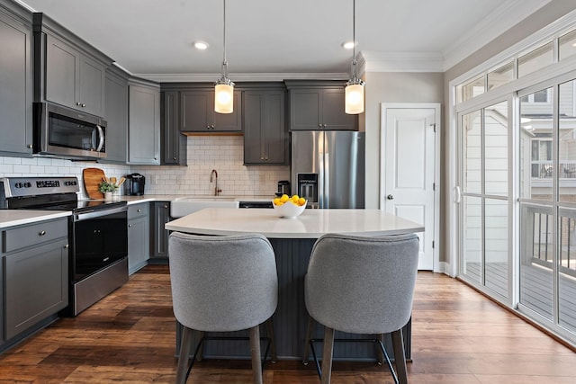 kitchen with sink, appliances with stainless steel finishes, decorative backsplash, a kitchen island, and decorative light fixtures