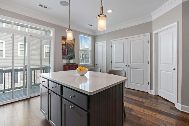 kitchen with decorative light fixtures, ornamental molding, dark hardwood / wood-style floors, and a kitchen island