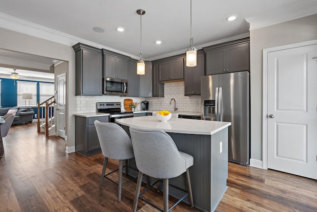 kitchen featuring crown molding, a kitchen breakfast bar, a kitchen island, pendant lighting, and stainless steel appliances