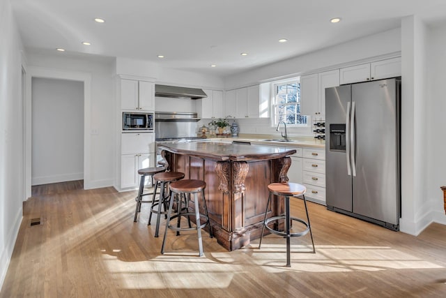 kitchen with stainless steel refrigerator with ice dispenser, ventilation hood, a center island, black microwave, and white cabinets