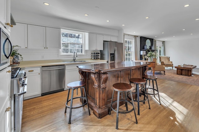 kitchen with white cabinetry, stainless steel appliances, sink, and light wood-type flooring