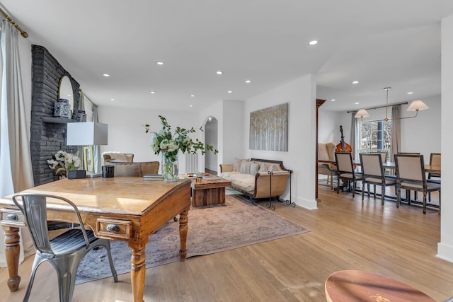 living room featuring a brick fireplace and light wood-type flooring