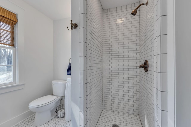 bathroom featuring a tile shower, tile patterned floors, and toilet