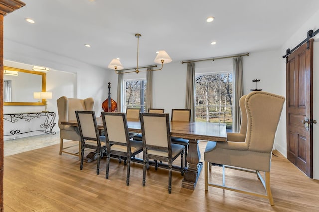 dining area featuring light hardwood / wood-style floors, a barn door, and a chandelier